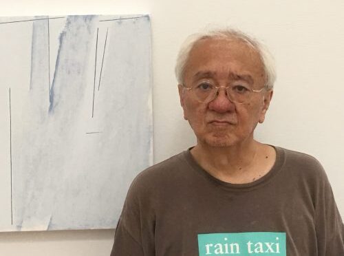 Color headshot of John Yau in front of a painting